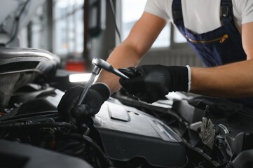 Fototapeta na wymiar Portrait Shot of a Handsome Mechanic Working on a Vehicle in a Car Service. Modern Clean Workshop.