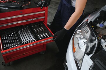 Auto mechanic working on car engine in mechanics garage. Repair service.