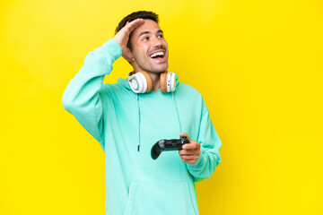 Young handsome man playing with a video game controller over isolated wall smiling a lot