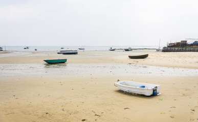 Fototapeta na wymiar Boats resting on the ocean's bed at low tide at the Cap Ferret along the Atlantic ocean's coastline