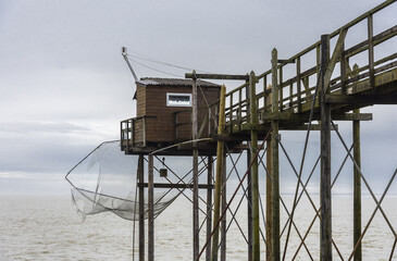 Fisherman's hut made of wood and resting on piles along the Atlantic ocean's coastline during a cloudy day