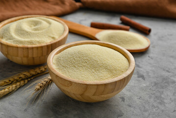 Bowls of raw semolina, cinnamon and spikelets on grunge background
