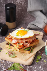 Delicious sandwich with fried egg and bacon on grey background