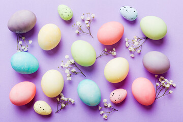 Happy Easter composition. Easter eggs on colored table with gypsophila. Natural dyed colorful eggs background top view with copy space