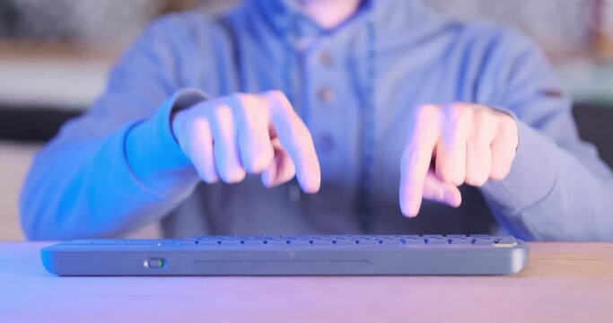 Man types on keyboard only with index fingers. Front view, blue-red flashing light. Concept of programming for dummies, abstraction, cyber criminal, hacker loser.