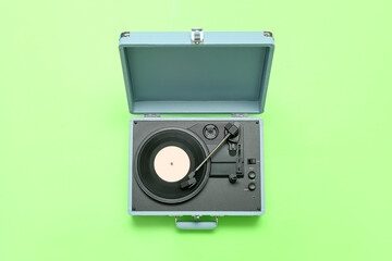 Record player with vinyl disk on green background