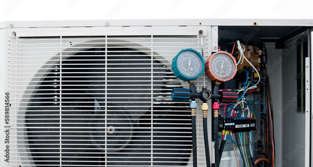 Wall mural technician is checking air conditioner,measuring equipment for filling air conditioners.