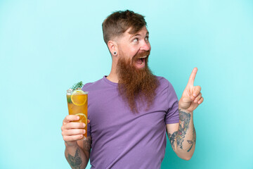 Fototapeta premium Redhead man with long beard holding a cocktail isolated on blue background intending to realizes the solution while lifting a finger up