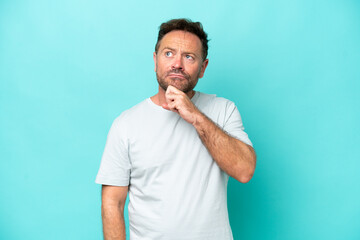 Middle age caucasian man isolated on blue background and looking up