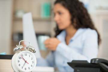 young businesswoman with alarm clock in office