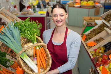 female greengrocer holding wicker basket of vegetbales