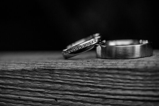 Grayscale of minimalist wedding bands together on the wooden round background