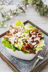 Bowl of BLT salad with lettuce, meat, bacon and avocados