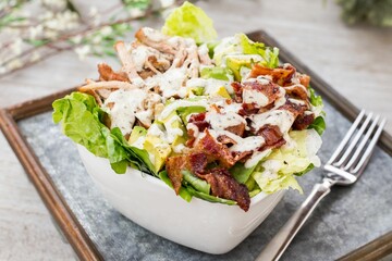 Bowl of BLT salad with lettuce, meat, bacon and avocados