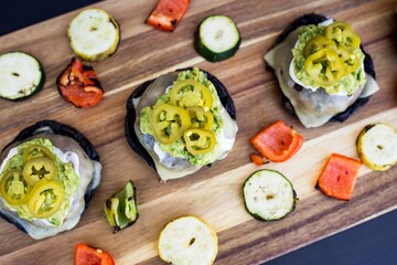 Top view of burger sliders with pickled jalapenos and grilled veggies on a wooden table