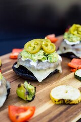 Vertical shot of burger sliders with pickled jalapenos and grilled veggies on a wooden table