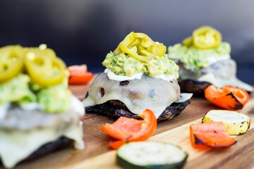 Closeup shot of burger sliders with pickled jalapenos and grilled veggies on a wooden table