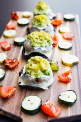 Vertical shot of burger sliders with pickled jalapenos and grilled veggies on a wooden table
