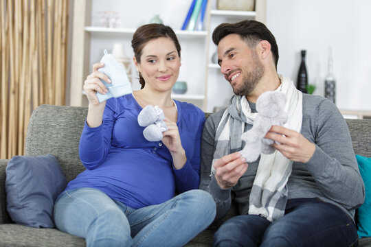 woman pregnant with her husband holding baby shoes