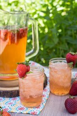 Vertical closeup shot of the two glasses of strawberry lemonade with ice, decorated by strawberries