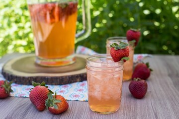 Closeup of the two glasses of strawberry lemonade with ice, decorated by strawberries