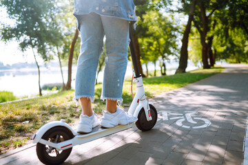 Women's legs on an electric scooter outdoors. Electric vehicles. Ecological transport. Active lifestyle. © maxbelchenko