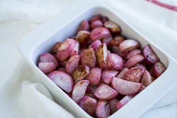 Closeup of the bowl of red sliced potatoes on a white fabric during the daytime
