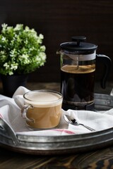 Vertical shot of a cup full of French Press Coffee on the tray on the blurred background