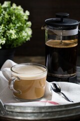 Vertical shot of a cup full of French Press Coffee on the tray on the blurred background