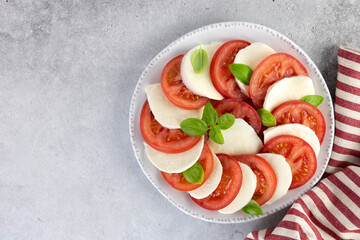 Italian caprese salad with tomatoes, mozzarella, basil on a blue background. Top view. Italian food.