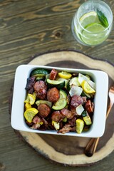 Vertical top view shot of a veggie salad on a white bowl with a glass of Mojito on a wooden table