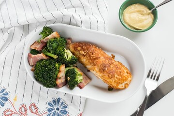 Top view of the chicken with broccoli and sliced meat on a white bowl with a fork and knife