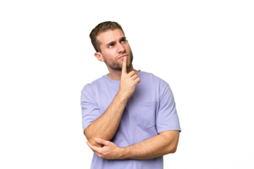 Young handsome caucasian man isolated on green chroma background having doubts while looking up