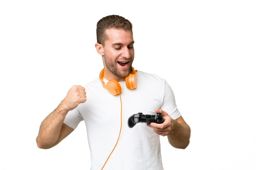 Young handsome man playing with a video game controller isolated on green chroma background celebrating a victory