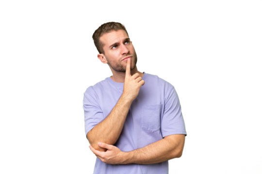 Young handsome caucasian man isolated on green chroma background having doubts while looking up