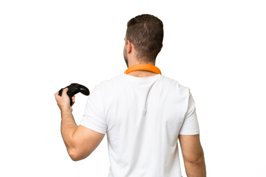 Young handsome man playing with a video game controller isolated on green chroma background in back position