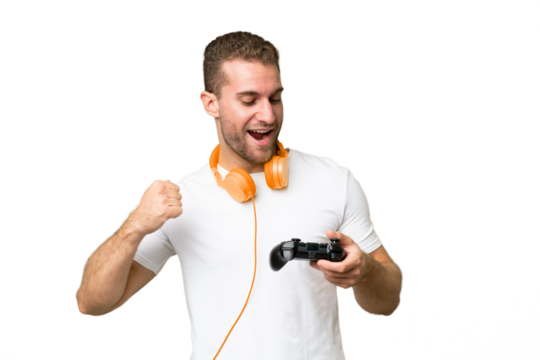 Young handsome man playing with a video game controller isolated on green chroma background celebrating a victory