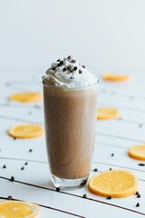 Vertical shot of a glass of frozen hot chocolate on a table with chocolate candies and oranges