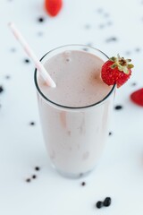 Closeup shot of a tall glass cup of raspberry milkshake with a pink straw on kitchen counter