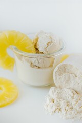 Vertical closeup shot of a glass of ice cream surrounded by sliced pineapples