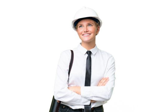 Young architect caucasian woman with helmet and holding blueprints over isolated background looking up while smiling