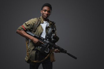 Shot of black soldier in post apocalyptic setting dressed in uniform and holding rifle.