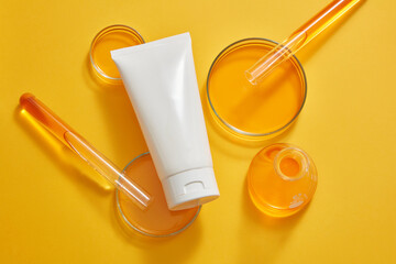 Petri dishes, test tubes and an erlenmeyer flask of orange liquid displayed with a white tube....