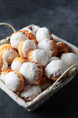 Baking for the Easter holiday. Cupcakes in large quantities are in the basket. White icing on cupcakes. Vertical photo.