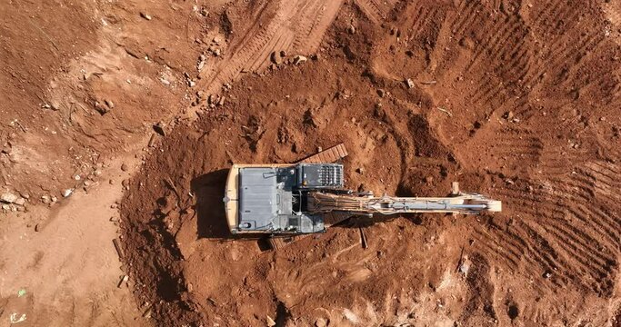 Aerial footage of Wheel Loader and a bagger working on a hill at a construction site and preparing the area for construction work. Filmed in C4K Apple ProRes 422 HQ