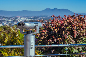 A telescope with a view of the city of Dalat Vietnam mountains flowers the background