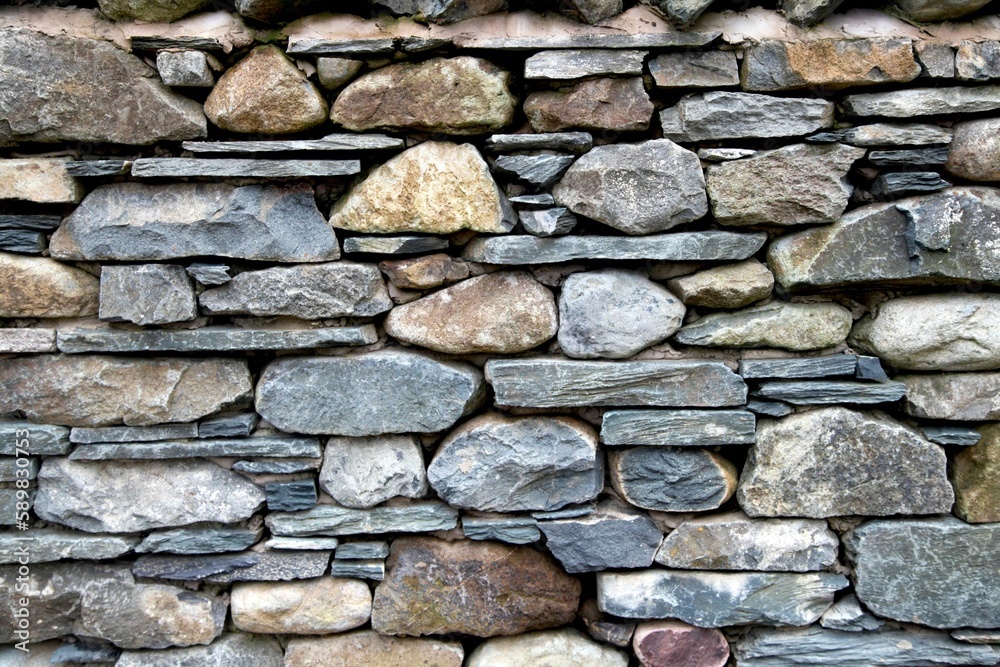 Wall mural Closeup shot of a gray stone wall with different rocks