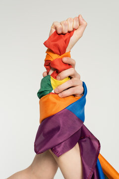 partial view of hands of nonbinary couple with lgbt flag isolated on grey.