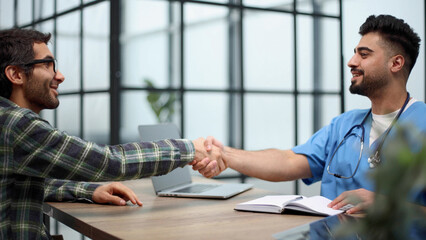 Nice doctor shaking hands with the patient