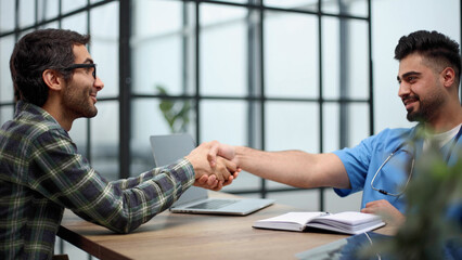 Nice doctor shaking hands with the patient